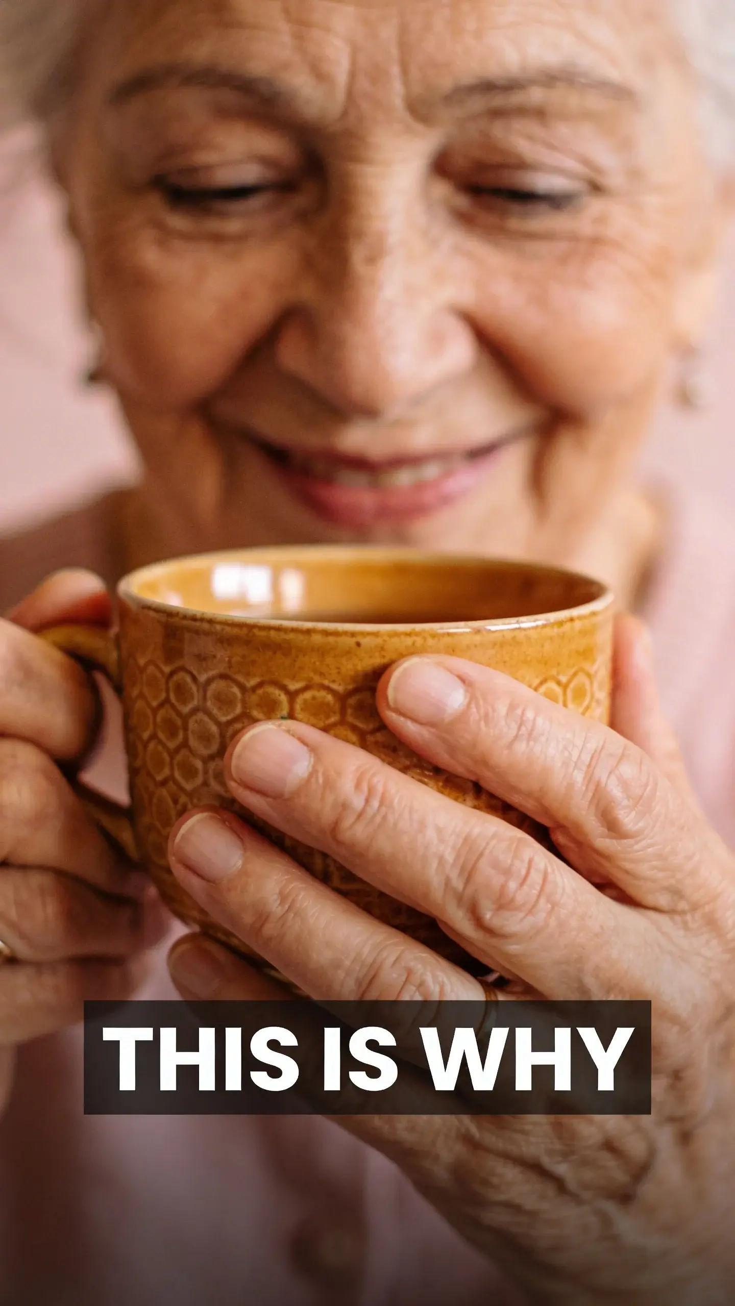 **MACRO EMOTION**: MACRO EMOTION, **BASE**: vertical 9:16, ultra-tall composition, **SCENE**: An extreme macro shot focusing on the intricate details of an elderly woman's hands, gently cradling a warm, textured ceramic teacup. The soft, diffused natural light highlights the subtle wrinkles and character lines, conveying a profound sense of contentment and peace as she savors her drink, with a hint of a genuine, soft smile playing on her lips just out of focus., **TEXT POSITION**: BOTTOM-CENTER, **OVERLAY**: text says exactly: "THIS IS WHY", bold readable font, high contrast white on dark, **LIGHT**: Soft, diffused natural light, **MOOD**: Tender, content, serene, warm, joyful, photorealistic, 8K, shallow depth of field, warm pastel tones, film aesthetic, no logos, no watermarks