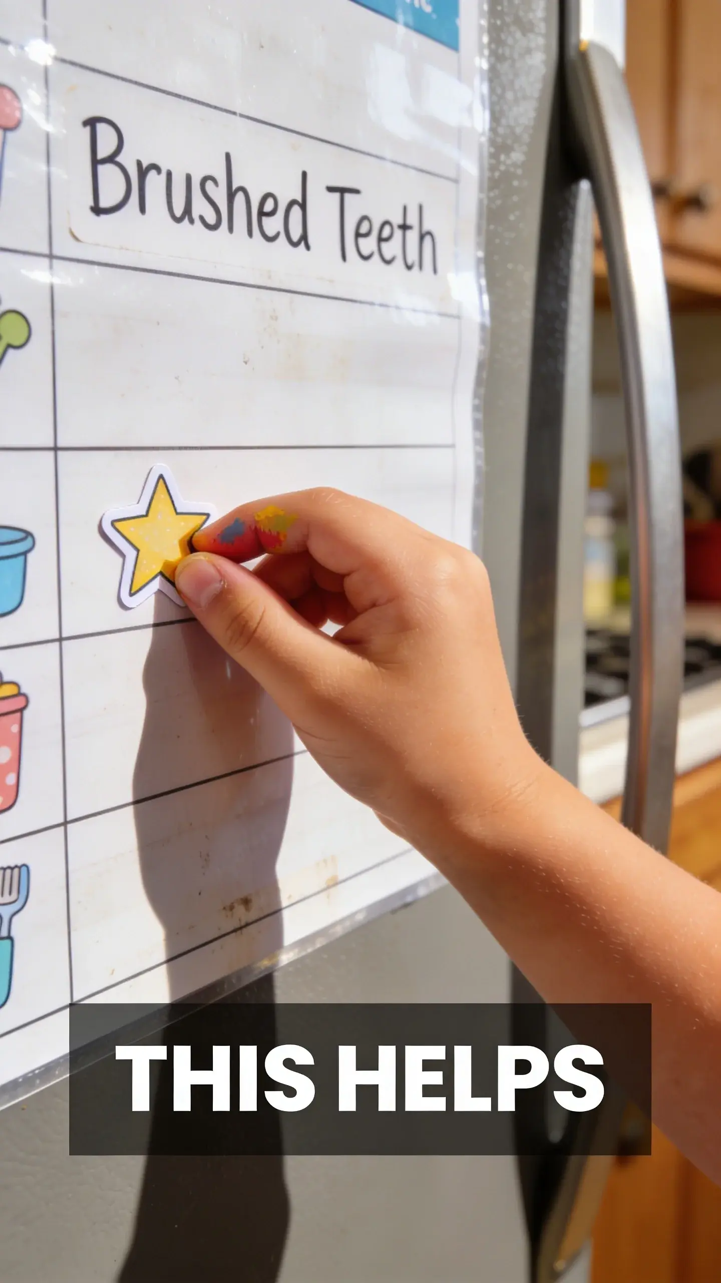 **MACRO EMOTION**: MACRO EMOTION, **BASE**: vertical 9:16, ultra-tall composition, **SCENE**: An extreme close-up (macro) on a child's small hand carefully placing a star sticker next to "Brushed Teeth" on a laminated morning routine chart attached to a refrigerator door. The chart is slightly worn from use, and the child's finger is slightly smudged with paint, showing a sense of accomplishment and independence on a sunny afternoon. **TEXT POSITION**: BOTTOM-CENTER, **OVERLAY**: text says exactly: "THIS HELPS", bold readable font, high contrast white on dark, **LIGHT**: Bright kitchen light, **MOOD**: Accomplished, independent, proud