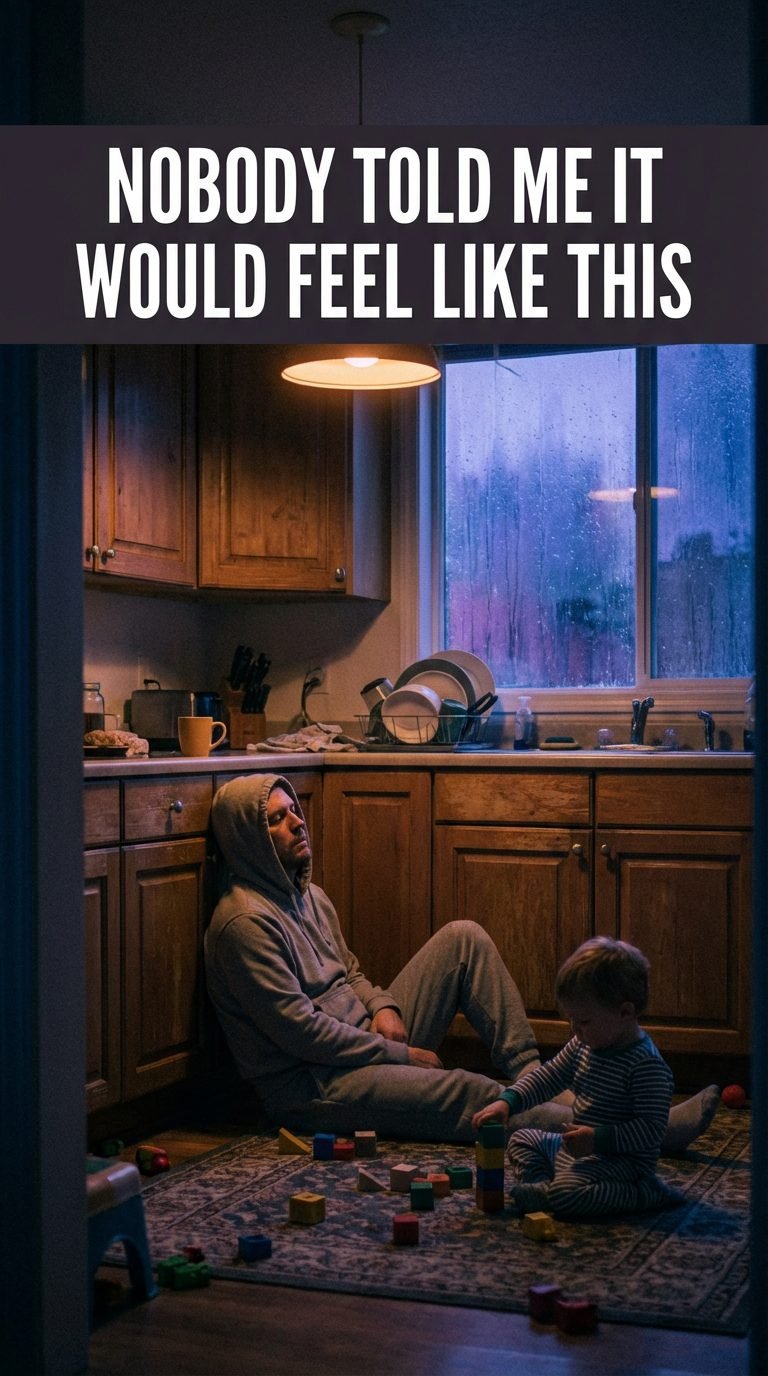 Exhausted parent sitting on kitchen floor at sunrise, back against cabinet, eyes closed, toddler playing nearby