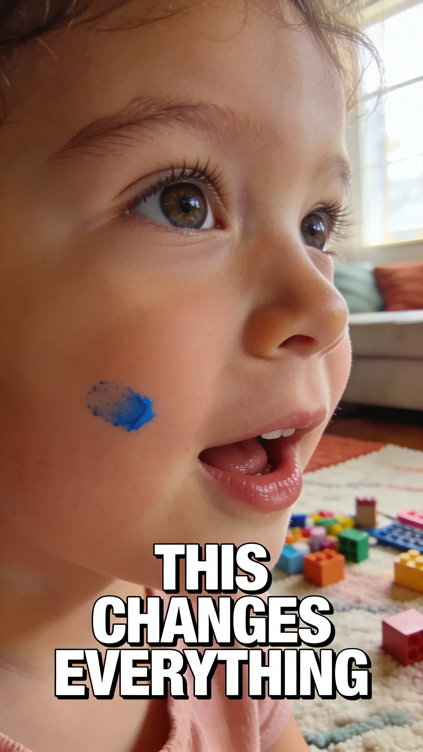**CLOSE-UP FACE EMOTION**: Close-up face emotion, vertical 9:16, ultra-tall composition optimized for mobile Pinterest feed, **SCENE**: An extreme close-up of a preschooler's face (around 3-4 years old), eyes wide with genuine delight and intense concentration. A tiny smudge of blue paint is visible on their left cheek, adding to the authenticity. Their gaze is fixed slightly off-camera, hinting at something they are actively creating or playing with, completely absorbed. Their mouth is slightly open in a small, joyful gasp or a focused, content expression. The background is a soft, dreamy blur of colorful craft supplies or building blocks on a cozy living room rug, emphasizing the child's joyful engagement. , **EMOTION HOOK**: Joy of screen-free play, **TOPIC PHRASE**: Fun screen-free ideas, **TEXT POSITION**: BOTTOM-CENTER, **OVERLAY**: text says exactly: "THIS CHANGES EVERYTHING", bold sans-serif font, high contrast white text with dark outline or shadow so it is readable on mobile, **LIGHT**: Soft morning window light illuminating the child's face, creating a gentle glow, **MOOD**: Joyful, engaged, curious, peaceful, content, **COLOR**: muted warm palette (dusty rose, cream, terracotta, soft sage, warm beige), gentle film grain, no logos, no watermarks, photorealistic, 8K, shallow depth of field, film aesthetic, cinematic color grade, no logos, no watermarks
