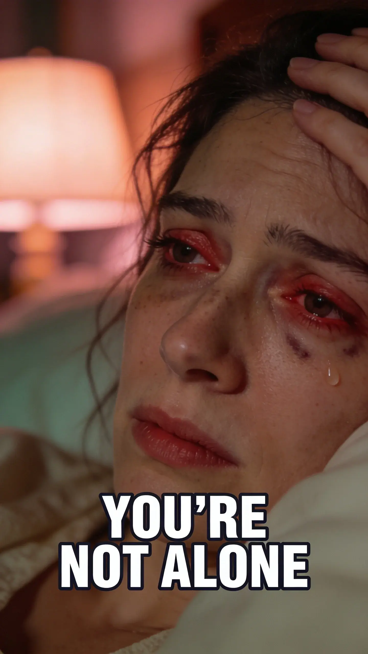 **CLOSE-UP FACE EMOTION**: close-up face emotion, vertical 9:16, ultra-tall composition optimized for mobile Pinterest feed, **SCENE**: An extreme close-up of a mother's face, late at night. Her eyes are slightly red-rimmed and heavy, with faint dark circles underneath. Her expression is a raw, intense mix of profound exhaustion, overwhelm, and a desperate, silent plea for sleep, perhaps with a single tear glistening at the corner of one eye. Her hair is slightly disheveled from being touched repeatedly. The background is a soft, warm blur of a dimly lit bedroom, hinting at the long night. **EMOTION HOOK**: utterly exhausted mom, **TOPIC PHRASE**: sleep struggle solutions, **TEXT POSITION**: BOTTOM-CENTER, **OVERLAY**: text says exactly: "YOU'RE NOT ALONE", bold sans-serif font, high contrast white text with dark outline or shadow so it is readable on mobile, **LIGHT**: warm, moody bedside lamp light, highlighting the contours of her face and the emotion in her eyes, **MOOD**: exhausted, overwhelmed, desperate, vulnerable, hopeful, **COLOR**: muted warm palette (dusty rose, cream, terracotta, soft sage, warm beige), gentle film grain, no logos, no watermarks, photorealistic, 8K, shallow depth of field, film aesthetic, cinematic color grade